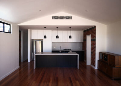 kitchen with black bench and cabinetry, dark accents, and exposed brick feature walls