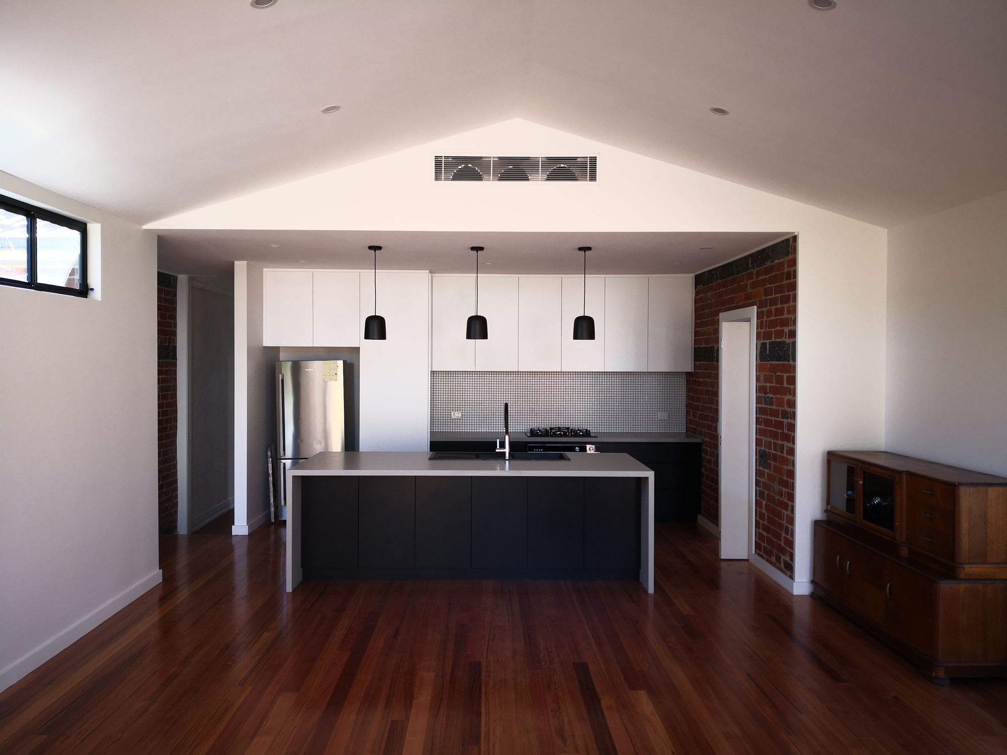 kitchen with black bench and cabinetry, dark accents, and exposed brick feature walls